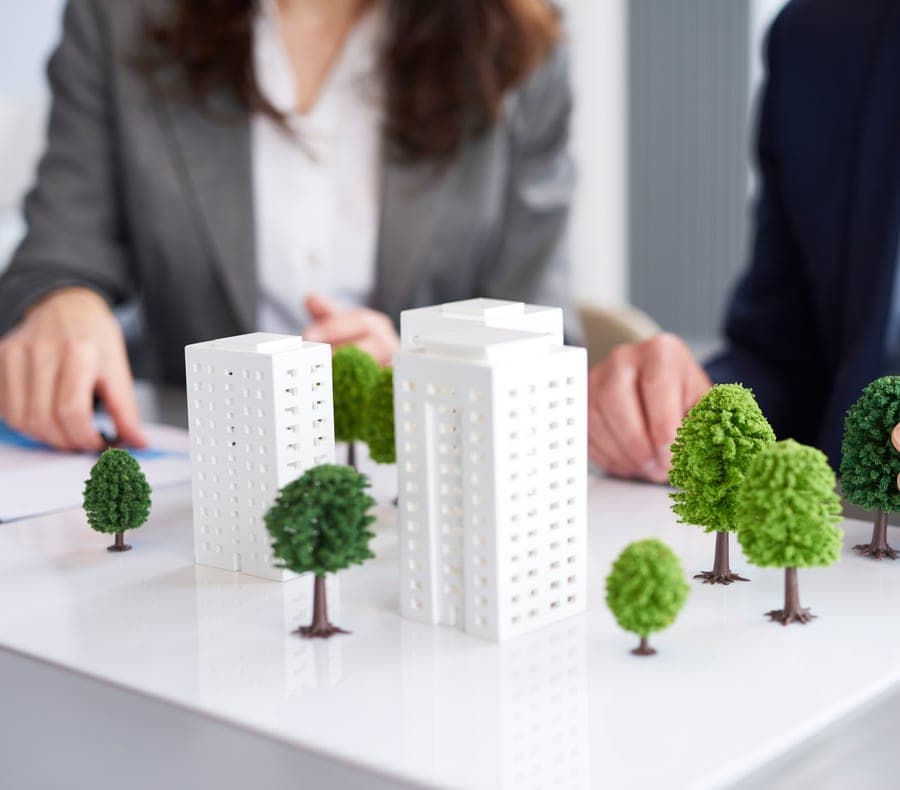 Scale models of buildings beside stacks of coins with small plants